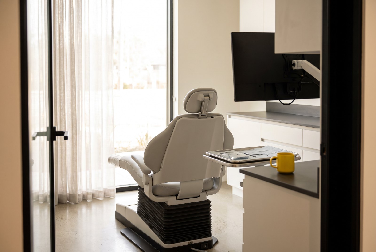 Salle de soins d’un cabinet dentaire au petit matin, fauteuil vide et lumière naturelle